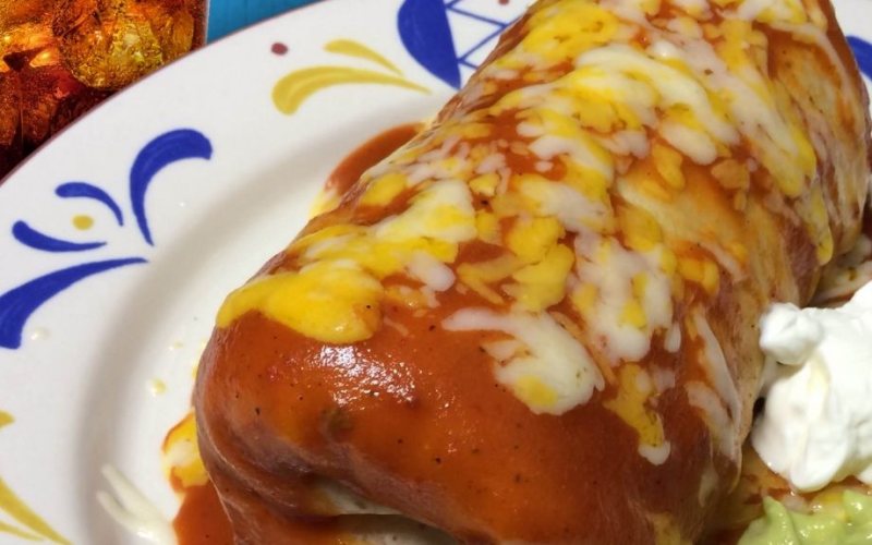 A Jr. Super Deluxe burrito smothered in red sauce and melted cheese, with sour cream