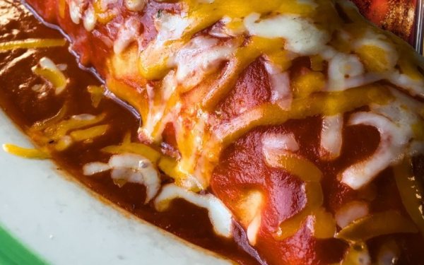 A Super Deluxe burrito covered in red sauce and melted cheese